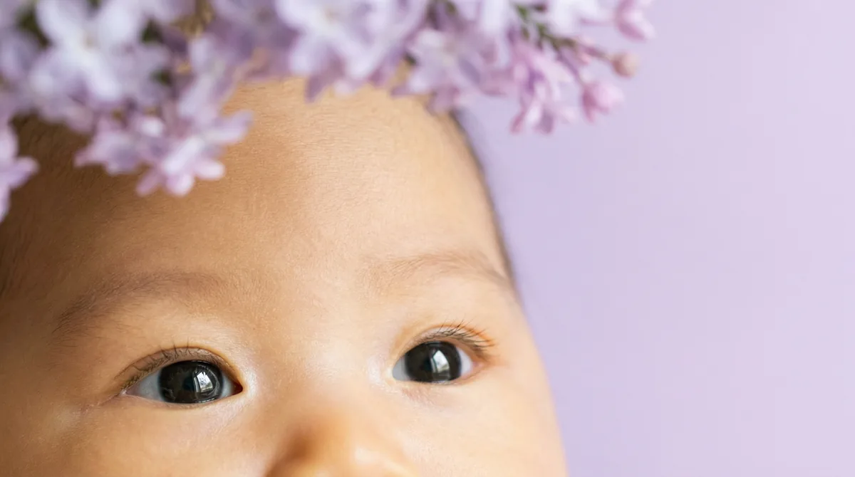 Artistic close-up of newborn baby with close up eyes lavender frame