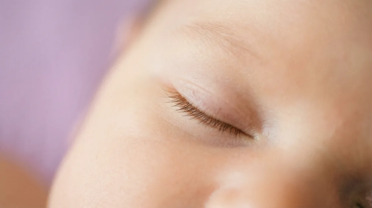 Artistic close-up of newborn baby with macro closed eyes lashes