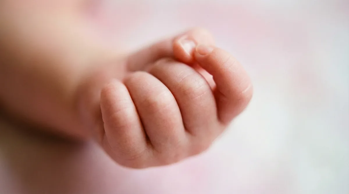 Artistic close-up of newborn baby with macro fingers fist